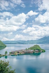 Vertical shot of a peninsula in Lugu lake under a blue sky with clouds in China.