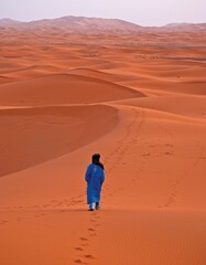 Fototapeta na wymiar Vertical back view of a male walking in the desert, Morocco, Africa