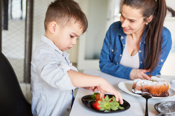Mother and son eating strawberries and cake