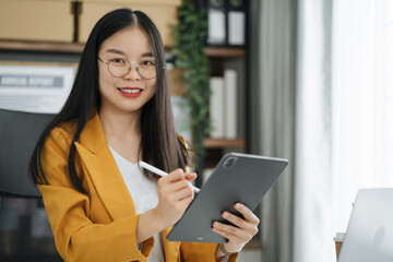 Female asian sitting at the desk, looking to camera.