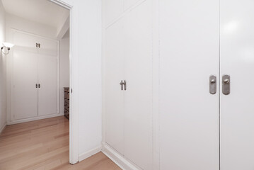 A dressing room with built-in wardrobes with white doors