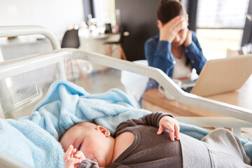 Obraz na płótnie Canvas Baby and exhausted single mom at pc