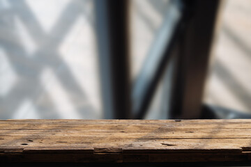 Empty wooden board on table top and blur inside over stucco wall blur background, mock up for display of goods.