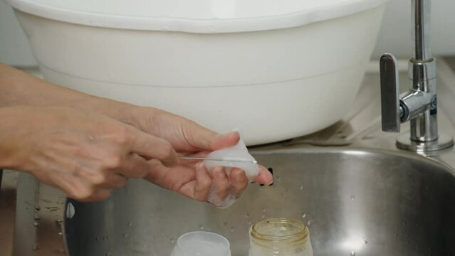 mother hand washing the baby plastic nipple of milk bottle