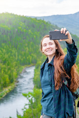 Smiling woman takes a selfie on the background of mountains and multinsky lake