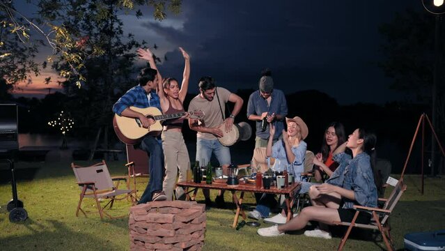 Group of friends playing guitar and drum enjoying with dancing in camping enjoy holiday vacation trip concept