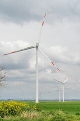 Vertical shot of wind turbines under the clouds in a green field during the day