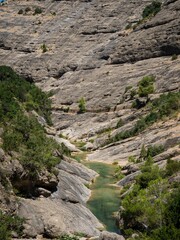 Obraz premium Vertical shot of a river surrounded by rocky mountains, Els Ports, Tarragona, Spain