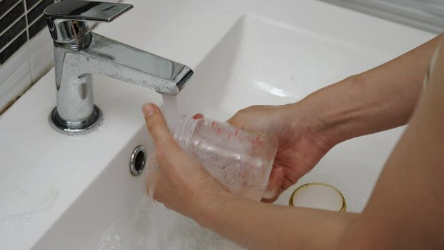 mother hand washing the baby plastic milk bottle