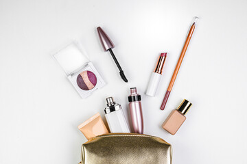 Golden cosmetic bag with makeup. Perfume, lip liner, lipstick, mascara, foundation. Vacation cosmetics.