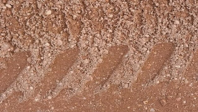 Footprint of car tire tread in a sand gravel road texture. Country road textured background. Backdrop for various ideas. Small stones land. Abstract sandy rough surface. Trendy effect. No people. Tyre