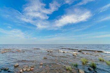 Fototapeta na wymiar Beautiful scenery of a lake with stones under the blue cloudy sky