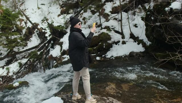 Middle aged woman hiker makes photos of the mountain riverside, 4k