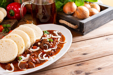 Traditional czech goulash with dumplings (knedliky) and beer on table. Place for text. Copy space