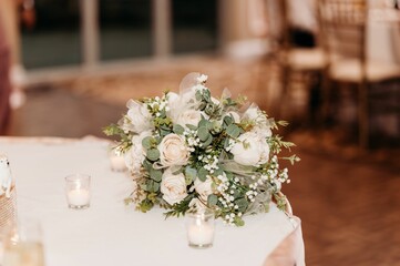 Selective focus of the wedding bouquet with white roses on the table with white candles