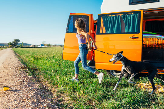 The happy girl with the dog has fun on a wonderful camping day. Van life concept.
