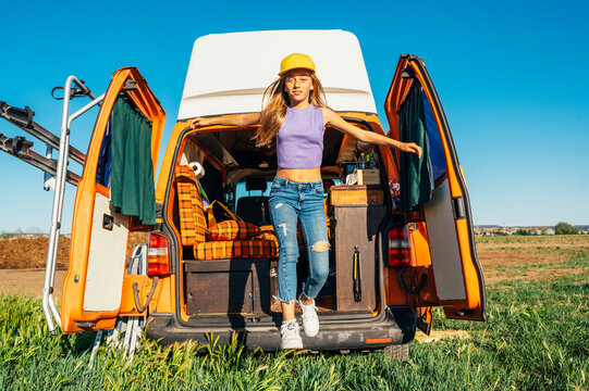 The happy girl has fun on a wonderful camping day. Van life concept.