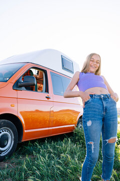 The happy girl has fun on a wonderful camping day. Van life concept.