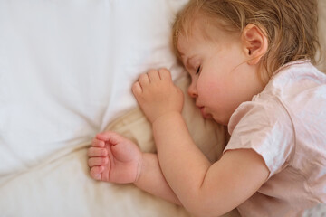 Peaceful adorable baby sleeping on his bed at home. Sleeping newborn baby concept. One year old baby girl sleeps peaceful at domestic room interior background. Serene dream. Cute Face Close Up