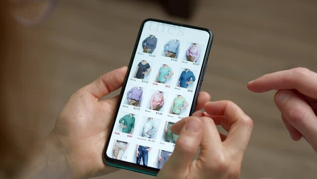 Shopping for clothes in online stores using a mobile phone. Hands of a woman and a man choosing a product on a smartphone screen. E-commerce.	