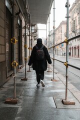 a woman in a black jacket is walking on the sidewalk