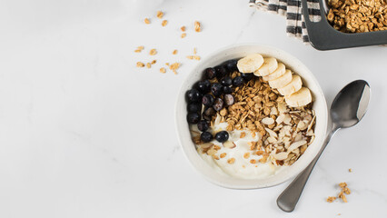 Homemade granola with Greek yogurt, almonds, blueberries and banana in a bowl. Copy space