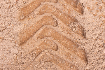 Footprint of car tire tread in a sand gravel road texture. Country road textured background. Backdrop for various ideas. Small stones land. Abstract sandy rough surface. Trendy effect. No people. Tyre