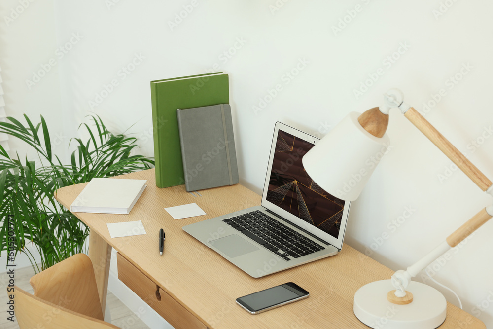 Poster Cozy workspace with laptop, smartphone and lamp on wooden desk at home