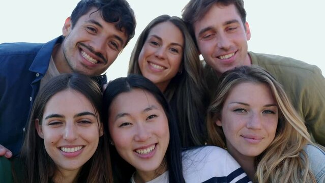 Diverse group portrait of friends smile at camera outdoors. Multiethnic young people having fun together. Millennial men and women enjoying summer travel. Friendship and youth community concept.