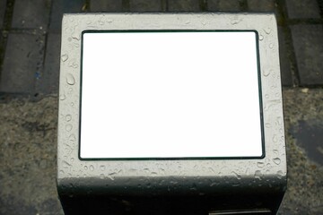 Closeup shot of a clean white screen with metal frame in a park with drain drops