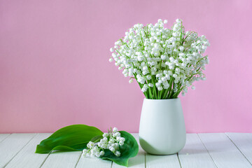 Naklejka premium Bouquet of beautiful lily of the valley flowers in a vase on a pink background