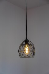Black pendant lamp shade hanging on ceiling, vertical shot