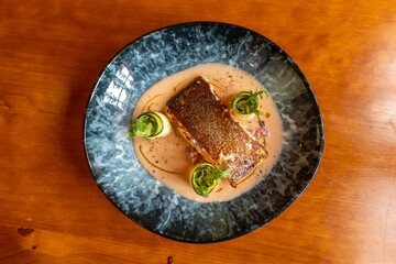 Top view of a pan fried salmon with cucumber rolls on a plate