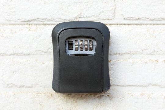Closeup of a key storage lock box on a white wall