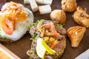 Closeup shot of cooked egg and steak sandwich placed on a wooden tray