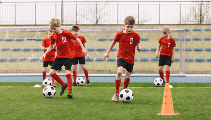 Young Boys at Soccer Training. Group of School Kids Kicking Soccer Balls During Practice Session. Children Improving Football Dribbling Skills Kicking Balls Between Cones