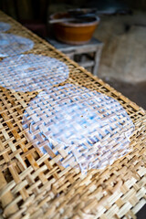 Fresh made ricepaper is drying on bamboo table for production of dumplings and spring rolls in the Cu Chi tunnels. Famous tourist attraction in Vietnam. Stock photo