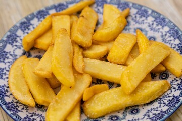Closeup shot of fried yellow potatoes in blue plate