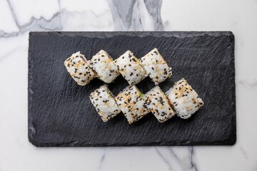 Closeup of Asian sushi rolls on black kitchen board