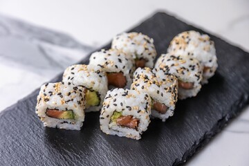 Closeup of Asian sushi rolls on black kitchen board