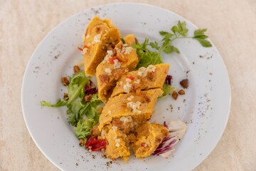 Top view of plate of delicious sliced chicken curry and greens on wooden table