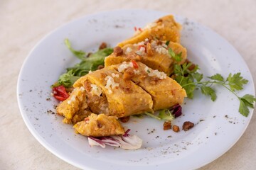 Closeup of plate of delicious sliced chicken curry and greens on wooden table