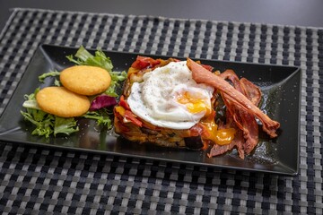 Closeup shot of a gourmet breakfast dish with fried egg, meat, and salad