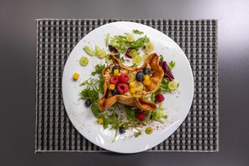 Top shot of a gourmet taco salad dish with raspberries, blueberries, and salad