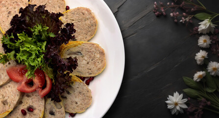 stuffed chicken with lettuce leaves and tomatoes. On a black background with flowers