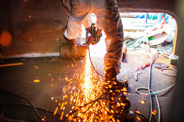 Male worker  grinding on steel plate with flash of sparks close up wear protective gloves oil inside