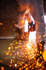 Male worker  grinding on steel plate with flash of sparks close up wear protective gloves oil inside