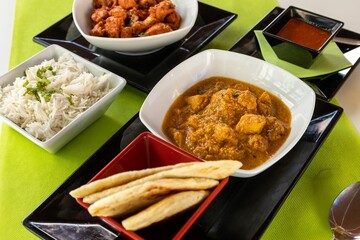 Closeup of different Indian dishes on white table with green tablecloth