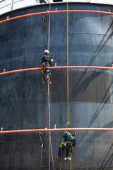 Male two worker rope down access safety inspection of pipe fire water repair storage tank
