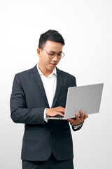 Portrait of smiling handsome young businessman in formal suit holding an open laptop in hand
